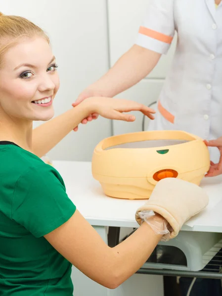 Woman getting paraffin hand treatment at beautician — Stock Photo, Image