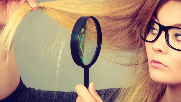 Woman holding magnifying glass looking at hair — Stock Photo, Image