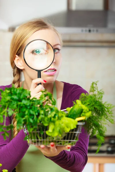 Woman looking through magnifier at vegetables basket — Stock Photo, Image