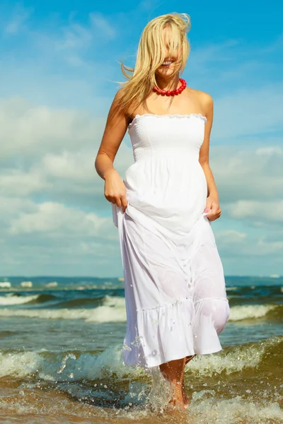 Blonde woman wearing dress walking in water — Stock Photo, Image