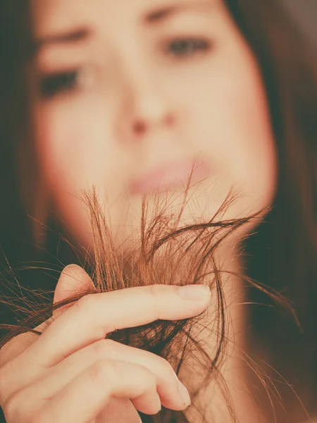 Mujer preocupada mirando sus puntas de cabello seco —  Fotos de Stock