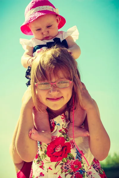 Małe dziecko dziewczyna dając jej młodsza siostra piggyback — Zdjęcie stockowe