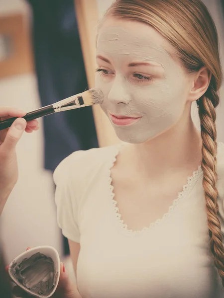 Happy young woman applying mud mask on face — Stock Photo, Image