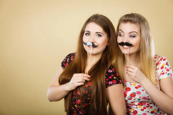 Duas mulheres felizes segurando bigode falso no pau — Fotografia de Stock