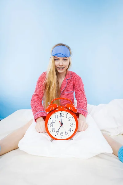 Сонная женщина в пижаме с часами — стоковое фото