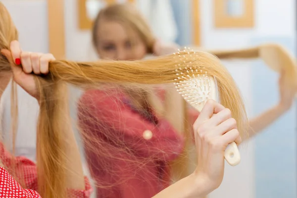 Vrouw borstelen van haar lange haren in de badkamer — Stockfoto