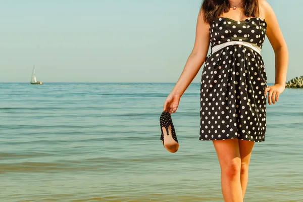 Mujer en vestido retro sosteniendo zapatos cerca del mar —  Fotos de Stock