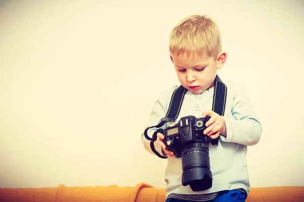 Ребенок играет с большой профессиональной цифровой камерой — стоковое фото
