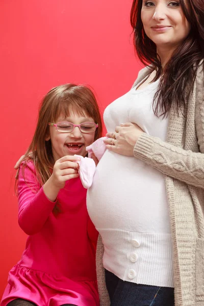 Femme enceinte avec tout-petit fille tenant des chaussures de bébé — Photo