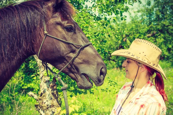 Westerse vrouw het verzorgen van het paard op weide — Stockfoto