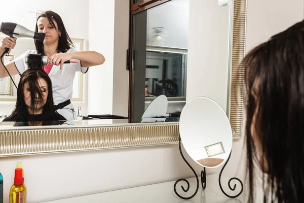 Frisören torkning mörka kvinnliga hår med hjälp av professionell hårtork — Stockfoto