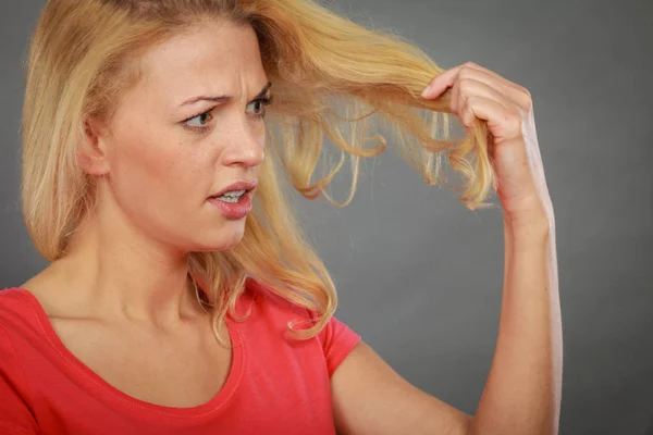 Traurige Frau blickt auf beschädigte Haarspitzen — Stockfoto