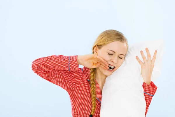 Junge Frau im Schlafanzug umarmt weiches Kissen — Stockfoto