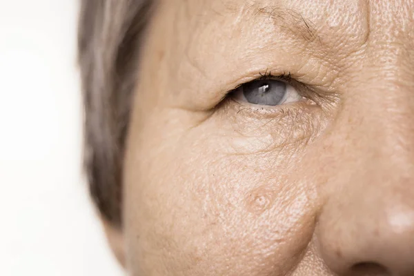 Bejaarde gepensioneerde m/v vrouwelijke helft van gezicht portret closeup — Stockfoto
