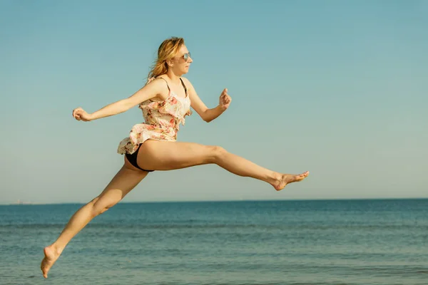 Mulher vestindo vestido brincando, pulando perto do mar — Fotografia de Stock