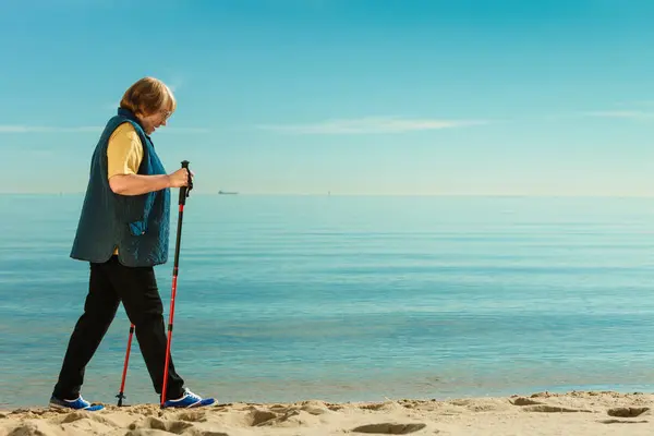 Seniorin übt Nordic Walking am Strand — Stockfoto