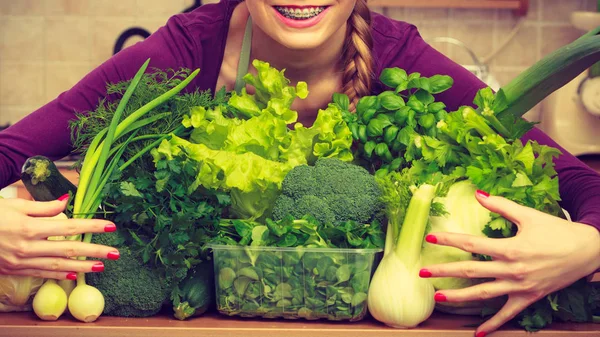 Usmívající se žena v kuchyni se zelenou zeleninou — Stock fotografie
