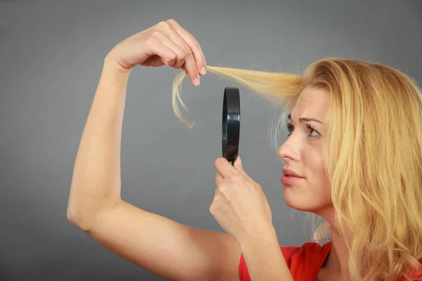 Woman looking at hair through magnifying glass — Stock Photo, Image