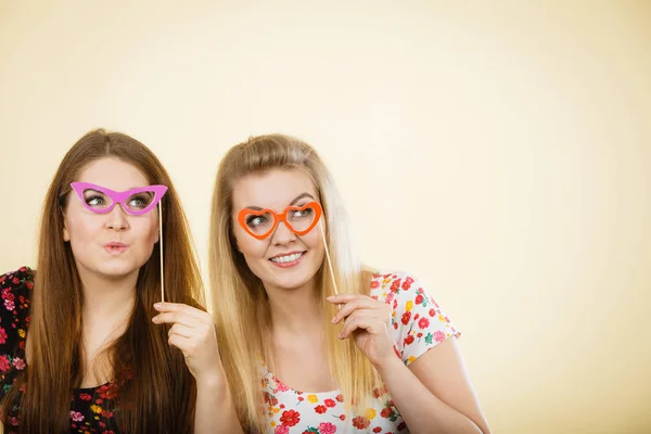 Twee gelukkige vrouwen houden van nep brillen op stick — Stockfoto