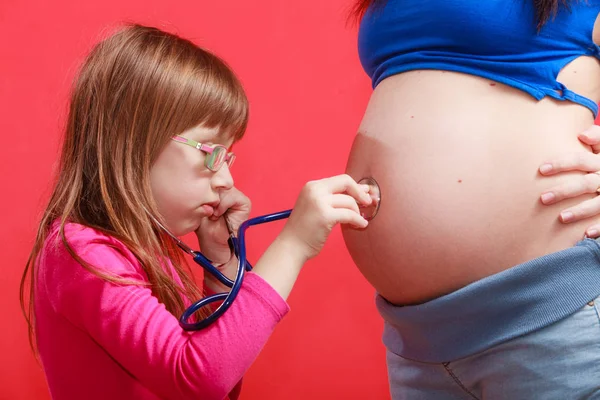 Hija usando estetoscopio en la madre embarazada — Foto de Stock