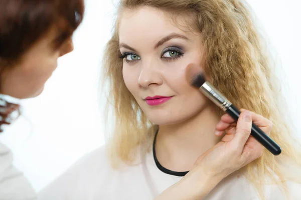 Artista de maquillaje aplicando con cepillo rouge en cheque femenino —  Fotos de Stock