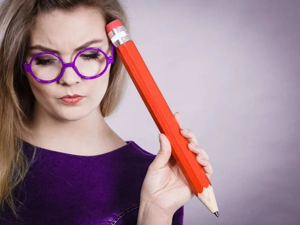 Mujer confundida pensando, lápiz grande en la mano — Foto de Stock