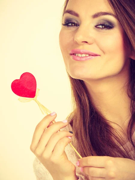 Flirty woman holding red wooden heart on stick — Stock Photo, Image