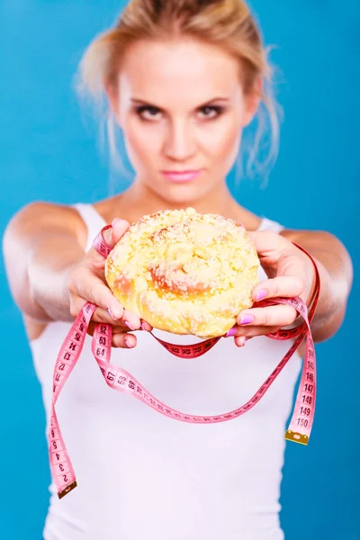 Woman holds sweet bun recommending non sugar diet — Stock Photo, Image