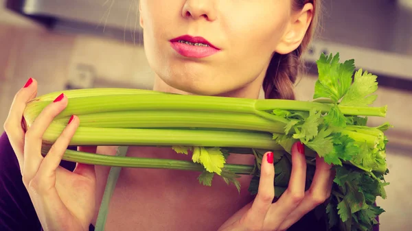 Mulher na cozinha detém aipo verde — Fotografia de Stock