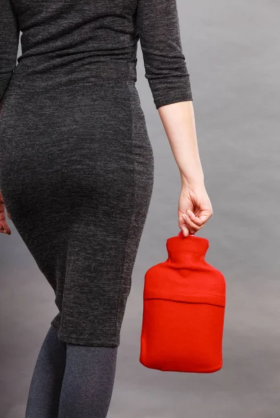 Kvinna som håller varm röd varmvattenflaska — Stockfoto