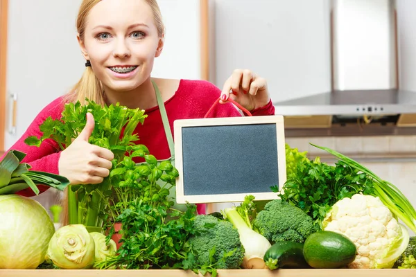 Kvinna med gröna grönsaker håller styrelsen — Stockfoto