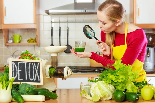 Kvinna som tittar på grönsaksjuice genom förstoringsglas — Stockfoto