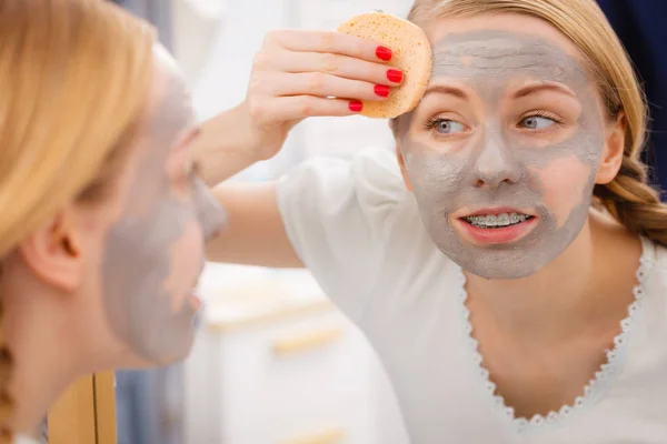 Kobieta, usuwanie błota maska do twarzy z gąbką — Zdjęcie stockowe