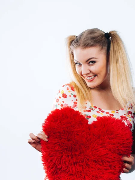Happy woman holding heart shaped pillow — Stock Photo, Image