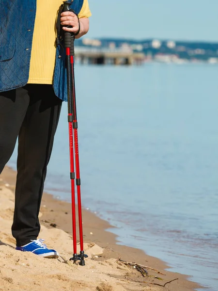 Senior woman practicing nordic walking on beach — Stock Photo, Image