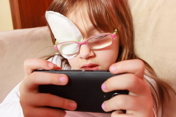 Toddler girl with bandage on eye playing games — Stock Photo, Image