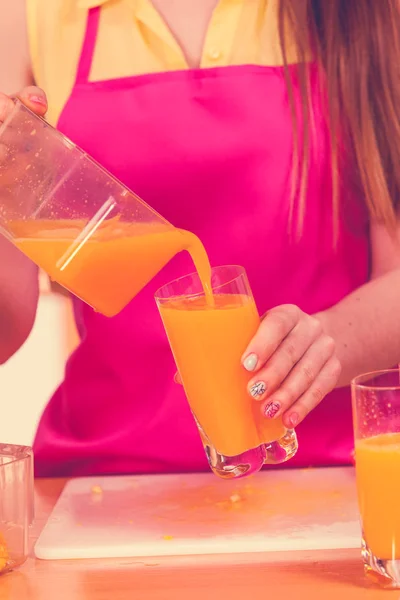 Woman pouring orange juice drink in glass — Stock Photo, Image