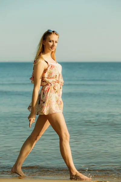 Kvinna i sommarklänning promenader på stranden — Stockfoto
