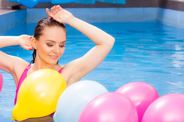 Woman having fun with balloons in water pool — Stock Photo, Image