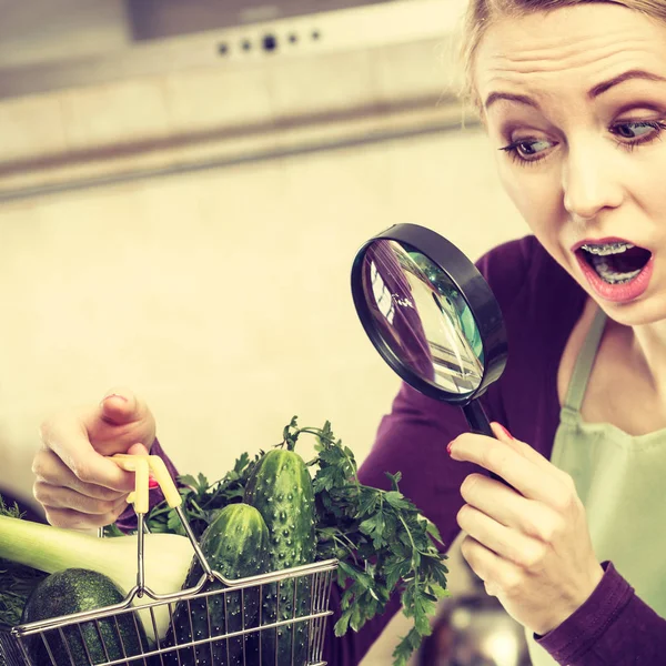 Kvinna söker förstoringsglas på grönsaker — Stockfoto