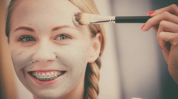 Жінка наносить пензлем глиняну грязьову маску на обличчя — стокове фото