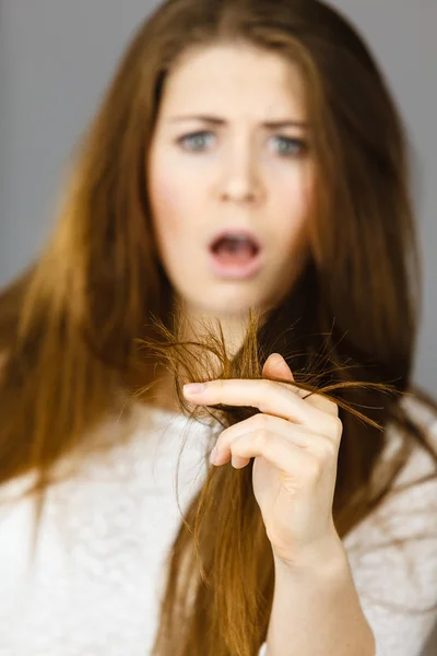 担心的女人看着她干的发梢 — 图库照片