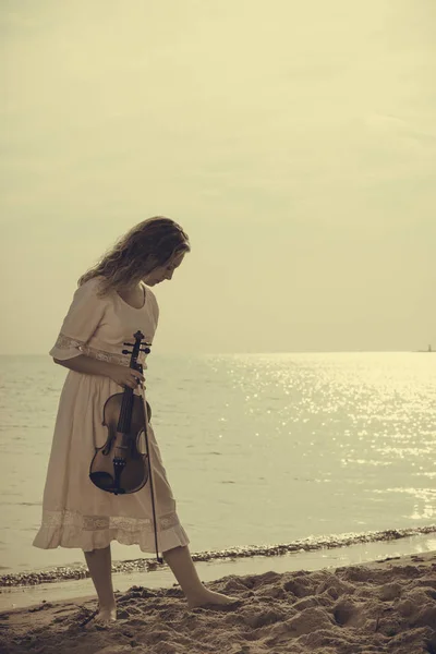 Mujer en la playa cerca del mar sosteniendo violín —  Fotos de Stock