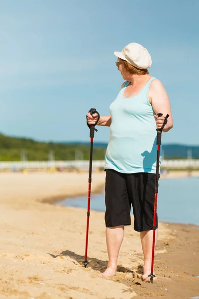 Mujer mayor practicando nordic walking en la playa —  Fotos de Stock