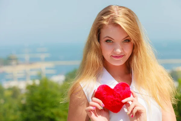 Feliz chica rubia sosteniendo almohada en forma de corazón — Foto de Stock