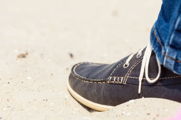 Par de zapatillas oscuras en la playa de arena —  Fotos de Stock