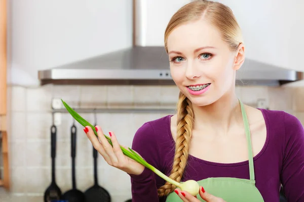 Kvinna i köket håller grön färsk gräslök — Stockfoto