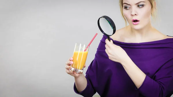 Женщина держит увеличительное стекло исследуя сок — стоковое фото