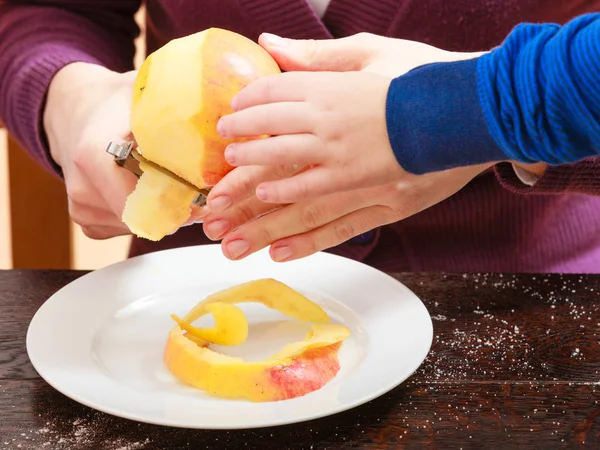 Niño y madre pelando manzanas con cuchillo — Foto de Stock