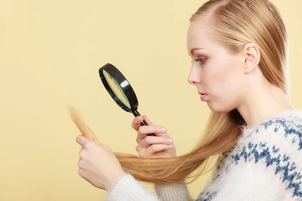 Treurige vrouw kijkt van beschadigd haar uiteinden. — Stockfoto